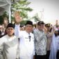 Wakil Wali Kota Payakumbuh Elzadaswarman (berbaju putih dan berpeci hitam) bersama Ketua DPRD Wirman Putra dan sejumlah pejabat serta tokoh masyarakat melambaikan tangan kepada Jamaah Calon Haji (JCH) Kota Payakumbuh Kloter XII yang diberangkatkan ke Embarkasi Padang, Jumat (23/5/2025). Keberangkatan jamaah disambut suasana haru oleh keluarga yang turut hadir di Gelanggang Pacu Kuda Payakumbuh.