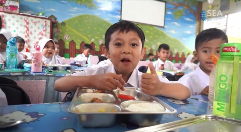 Siswa sekolah dasar di salah satu ruang kelas menikmati makanan dari program Makan Bergizi Gratis, Jumat (03/10/2025). Meski terlihat ceria, program ini menuai kritik setelah maraknya kasus keracunan massal dan dugaan keuntungan miliaran rupiah bagi pengusaha penyedia layanan.