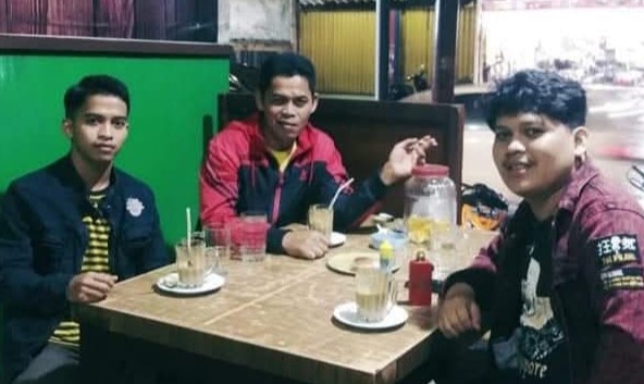 Aditia Alfiki (kiri) dan Arik Alfiki (kanan) bersama ayah mereka, Dedi Hendri (tengah), di sebuah warung sederhana di kawasan Pasar Ibuh, Payakumbuh. Dua bersaudara ini menorehkan prestasi di tingkat dunia setelah diakui oleh Apple Inc. dan NASA atas kontribusi mereka dalam bidang keamanan siber.
